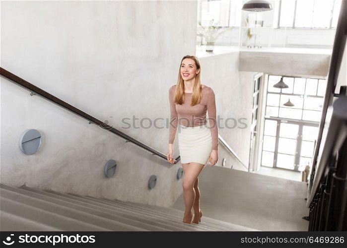 people, business and career concept - happy smiling woman walking upstairs. happy smiling woman walking upstairs