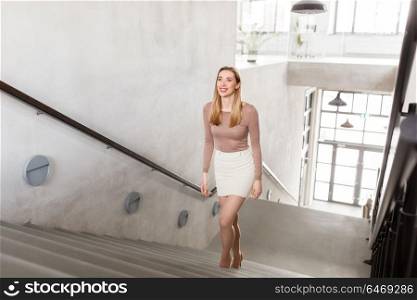 people, business and career concept - happy smiling woman walking upstairs. happy smiling woman walking upstairs