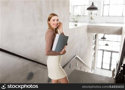 people, business and career concept - happy smiling woman with folder walking downstairs. happy woman with folder walking downstairs
