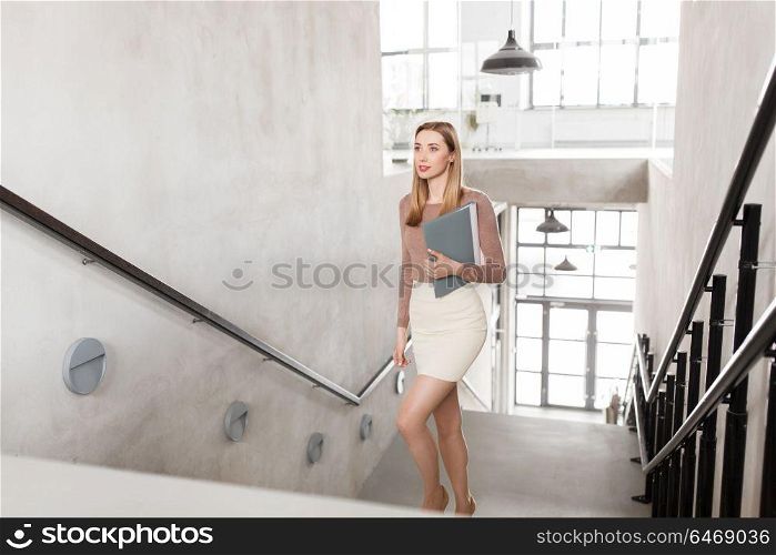 people, business and career concept - happy smiling woman with folder walking upstairs. happy woman with folder walking upstairs