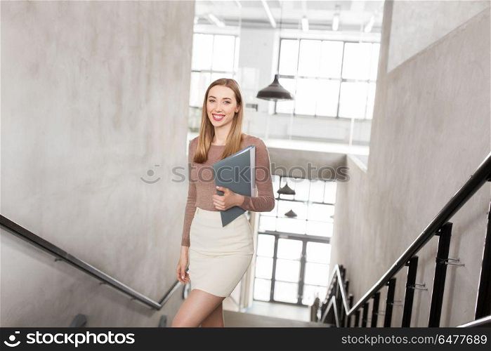 people, business and career concept - happy smiling woman with folder walking upstairs. happy woman with folder walking upstairs. happy woman with folder walking upstairs