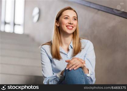 people, business and education concept - happy smiling woman or student sitting on stairs. happy smiling woman or student sitting on stairs