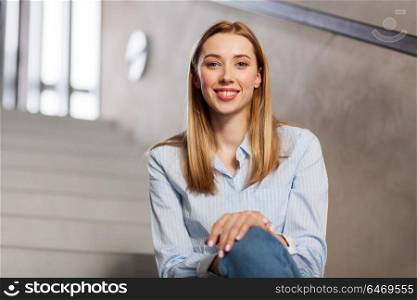 people, business and education concept - happy smiling woman or student sitting on stairs. happy smiling woman or student sitting on stairs