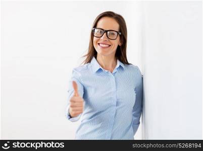 people, business and gesture concept - happy smiling middle aged woman in glasses showing thumbs up. happy smiling woman in glasses showing thumbs up
