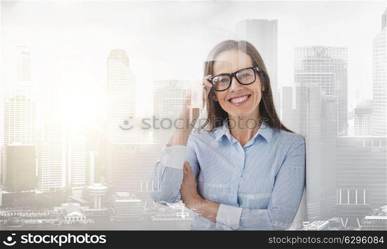 people, business and office concept - happy smiling middle aged woman in glasses over city buildings background and double exposure effect. happy smiling middle aged woman in glasses