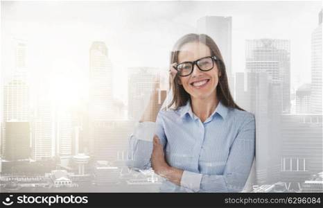 people, business and office concept - happy smiling middle aged woman in glasses over city buildings background and double exposure effect. happy smiling middle aged woman in glasses