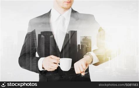 people, business and time concept - close up of businessman with wristwatch and coffee over city with double exposure. close up of businessman with wristwatch and coffee