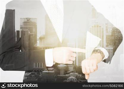 people, business and time concept - close up of businessman with wristwatch over city with double exposure. close up of businessman with wristwatch