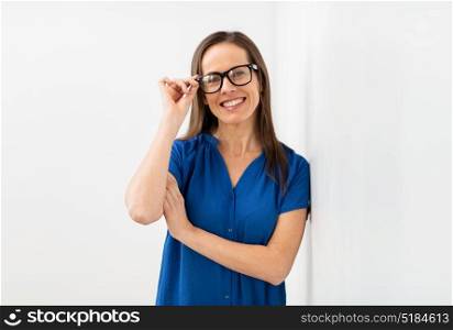 people, business and vision concept - happy smiling middle aged woman in glasses at office. happy smiling middle aged woman in glasses