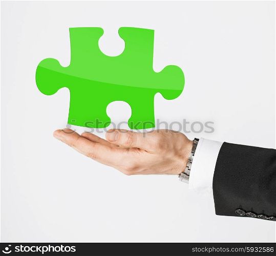 people, business, ecology and green energy concept - close up of male hand holding green puzzle piece