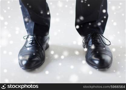 people, business, fashion and footwear concept - close up of man legs in elegant shoes with laces or lace boots over snow effect over snow effect