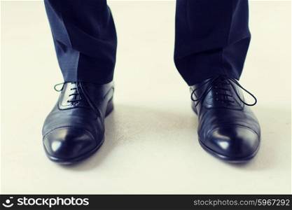 people, business, fashion and footwear concept - close up of man legs in elegant shoes with laces or lace boots