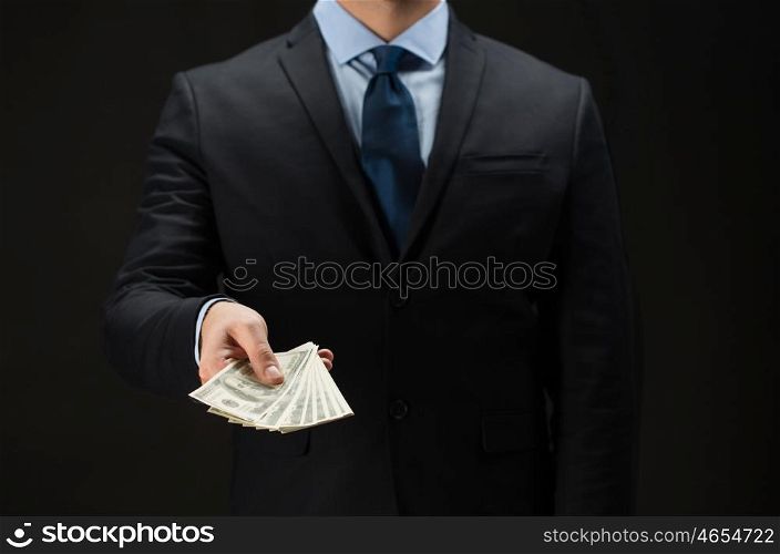 people, business, finances and money concept - close up of businessman hands holding dollar cash over black background