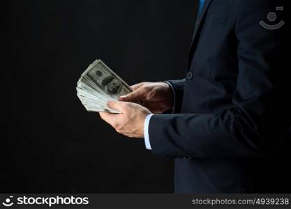 people, business, finances and money concept - close up of businessman hands holding dollar cash over black background. close up of businessman hands holding money