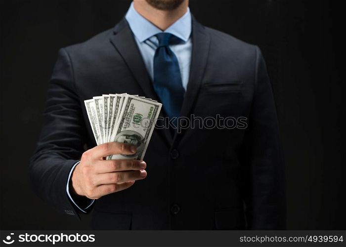 people, business, finances and money concept - close up of businessman hands holding dollar cash over black background. close up of businessman hands holding money