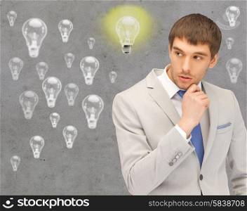 people, business, idea and doubts concept - young businessman thinking over gray background and light bulbs