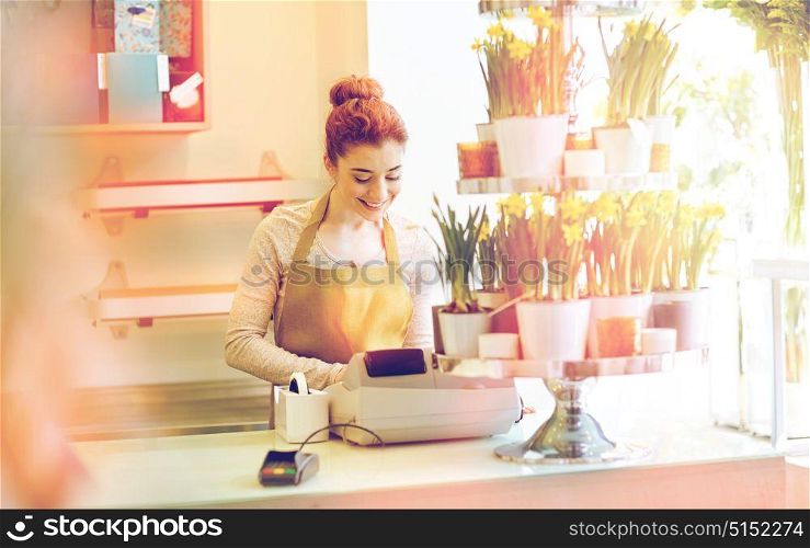 people, business, sale and floristry and concept - happy smiling florist woman at flower shop cashbox on counter. florist woman at flower shop cashbox on counter
