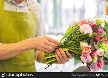 people, business, sale and floristry concept - close up of florist man making bunch at flower shop