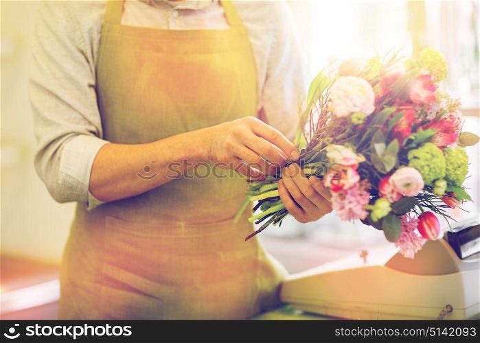 people, business, sale and floristry concept - close up of florist man making bunch at flower shop. close up of man making bunch at flower shop