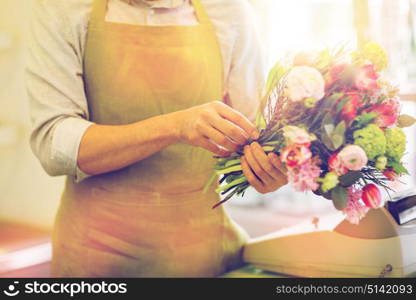 people, business, sale and floristry concept - close up of florist man making bunch at flower shop. close up of man making bunch at flower shop