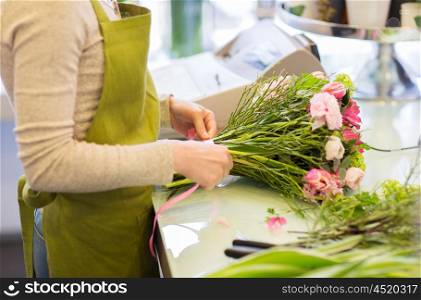 people, business, sale and floristry concept - close up of florist woman making bunch at flower shop
