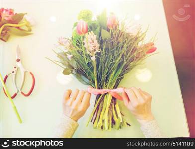 people, business, sale and floristry concept - close up of florist woman making bunch at flower shop. close up of woman making bunch at flower shop