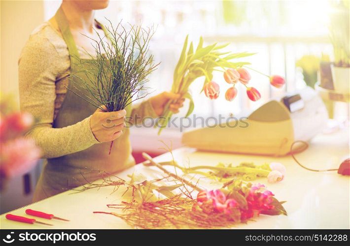 people, business, sale and floristry concept - close up of florist woman making tulip bunch at flower shop. close up of florist making bunch at flower shop