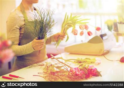 people, business, sale and floristry concept - close up of florist woman making tulip bunch at flower shop. close up of florist making bunch at flower shop