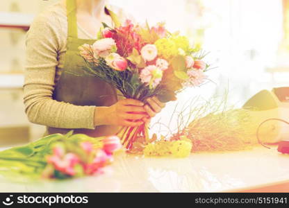 people, business, sale and floristry concept - close up of florist woman making bunch at flower shop. close up of woman making bunch at flower shop