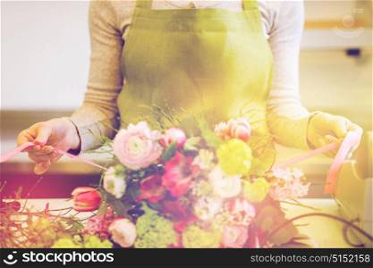 people, business, sale and floristry concept - close up of florist woman making bunch at flower shop. close up of woman making bunch at flower shop