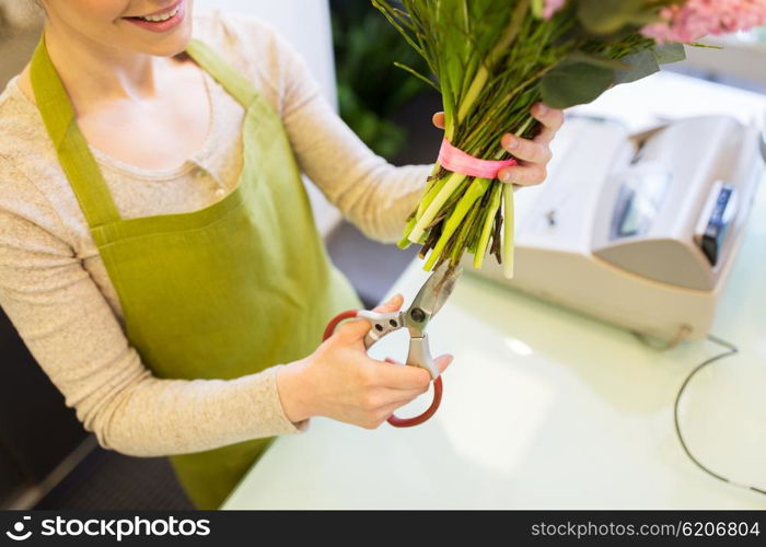 people, business, sale and floristry concept - close up of florist woman making bunch and cropping stems by scissors at flower shop
