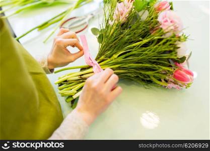 people, business, sale and floristry concept - close up of florist woman making bunch at flower shop