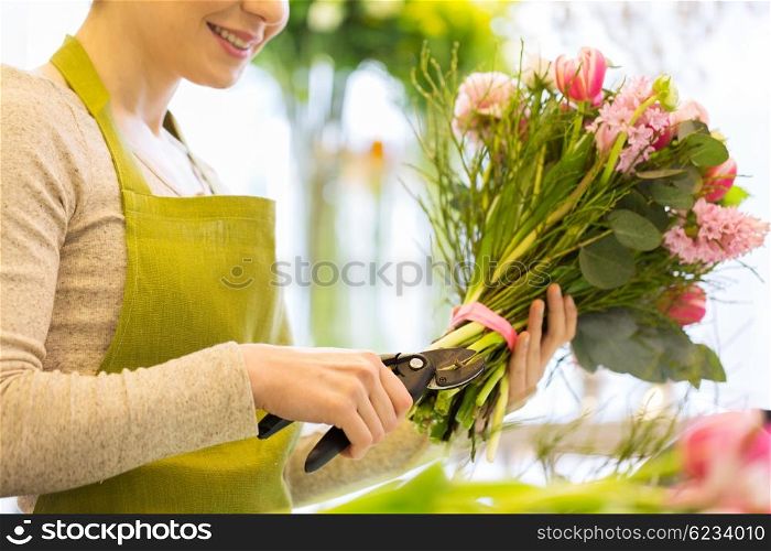 people, business, sale and floristry concept - close up of florist woman making bunch and cropping stems by pruner at flower shop