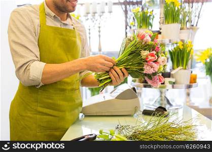 people, business, sale and floristry concept - close up of happy smiling florist man making bunch at flower shop