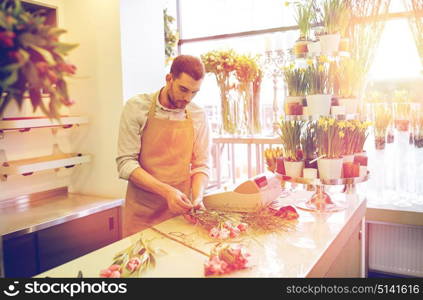 people, business, sale and floristry concept - florist man making bunch at flower shop. florist man making bunch at flower shop