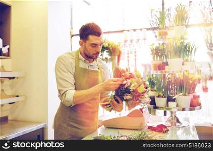 people, business, sale and floristry concept - florist man making bunch at flower shop. florist man making bunch at flower shop