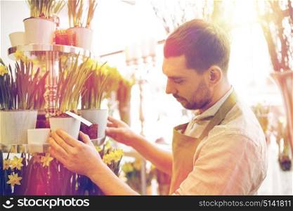 people, business, sale and floristry concept - florist man setting flowers at flower shop. florist man setting flowers at flower shop