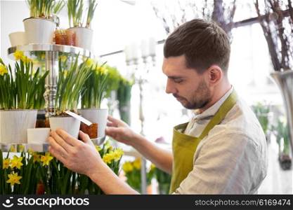 people, business, sale and floristry concept - florist man setting flowers at flower shop