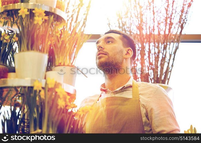 people, business, sale and floristry concept - florist man with narcissus flowers at flower shop. florist man with narcissus flowers at flower shop