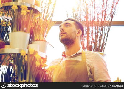 people, business, sale and floristry concept - florist man with narcissus flowers at flower shop. florist man with narcissus flowers at flower shop