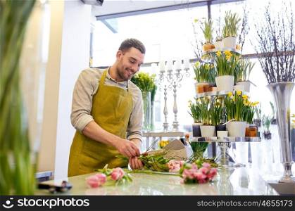 people, business, sale and floristry concept - happy smiling florist man making bunch at flower shop