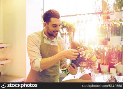 people, business, sale and floristry concept - happy smiling florist man making bunch at flower shop. smiling florist man making bunch at flower shop