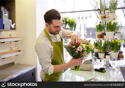 people, business, sale and floristry concept - happy smiling florist man making bunch at flower shop