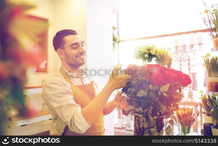 people, business, sale and floristry concept - happy smiling florist man with red roses at flower shop. smiling florist man with roses at flower shop