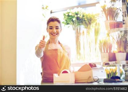 people, business, sale and floristry concept - happy smiling florist woman at flower shop cashbox showing thumbs up . florist woman at flower shop showing thumbs up