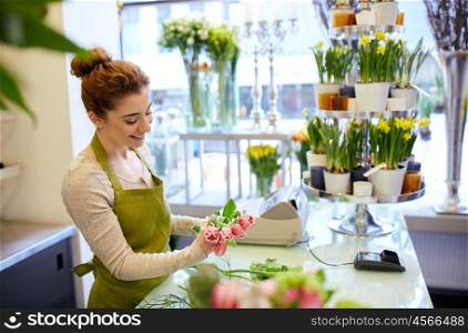 people, business, sale and floristry concept - happy smiling florist woman making tulip bunch at flower shop