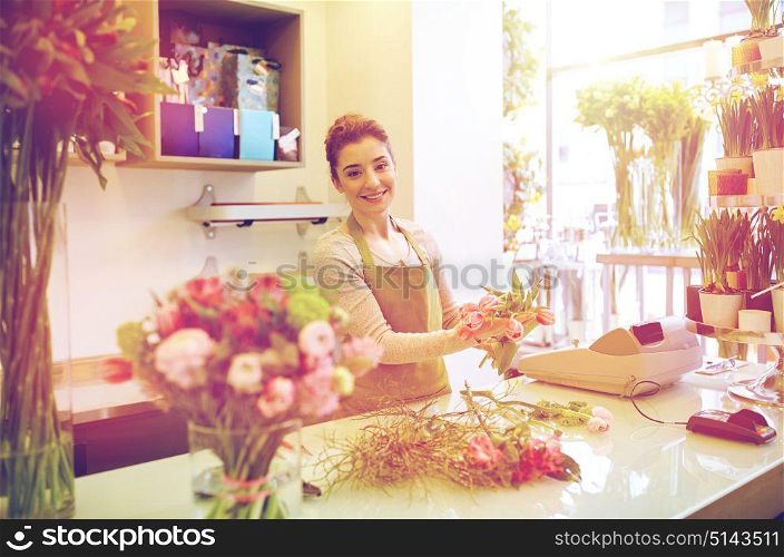 people, business, sale and floristry concept - happy smiling florist woman making tulip bunch at flower shop. smiling florist woman making bunch at flower shop