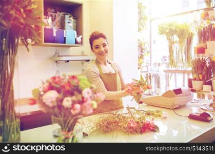 people, business, sale and floristry concept - happy smiling florist woman making tulip bunch at flower shop. smiling florist woman making bunch at flower shop