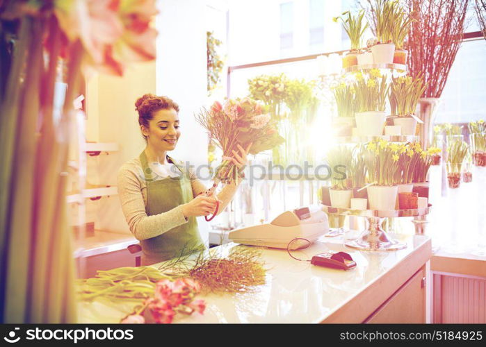 people, business, sale and floristry concept - happy smiling florist woman making bunch and cropping stems by scissors at flower shop. smiling florist woman making bunch at flower shop