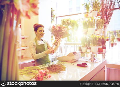 people, business, sale and floristry concept - happy smiling florist woman making bunch and cropping stems by scissors at flower shop. smiling florist woman making bunch at flower shop